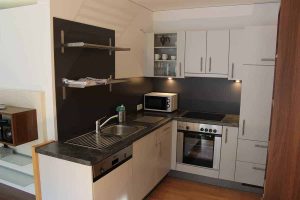 Helles Wohnzimmer mit moderner Einrichtung und Panoramafenster in einer Ferienwohnung Pettneu