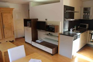 Helles Wohnzimmer einer modernen Ferienwohnung mit Sofa, Esstisch und Panoramafenster in Pettneu